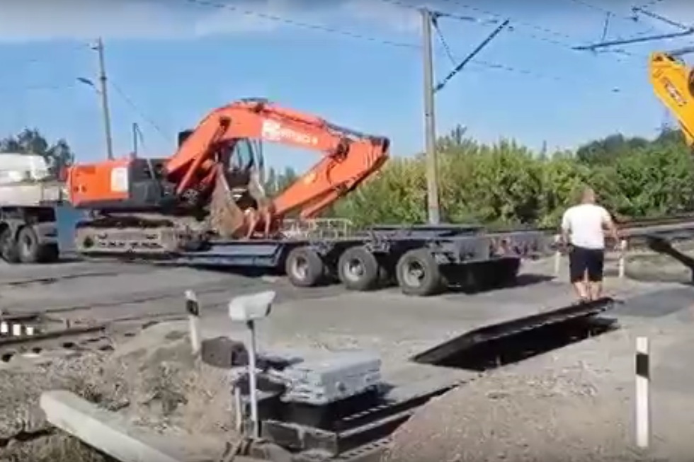На железнодорожном переезде в Ленинском районе перед двумя поездами застрял груженый строительной техникой тягач (видео)