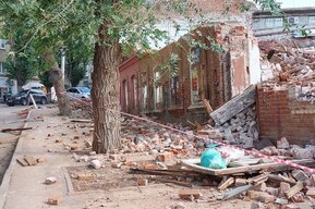 В Саратове уже два месяца сносят дом, который мог стать памятником: оградить жителей от летящих кирпичей нужным не посчитали (вместо забора — обрывки ленты и доски)